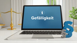 Laptop screen shows the German word 'Gefälligkeit' on a blue background, with a gold balance scale to the left and a large blue ampersand on the right.
