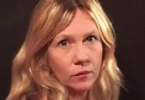 Close-up of a woman with long blonde hair looking straight at the camera.