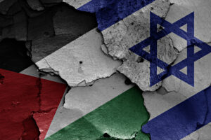 Cracked concrete wall painted with a collage of flags, featuring Israel's blue Star of David and blue stripes amid red and green areas.