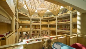 Open, multi‑level library atrium with a wooden geodesic skylight and people studying. (informative)