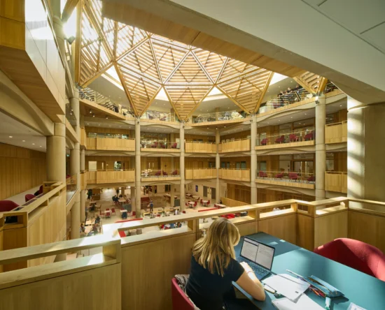 Open, multi‑level library atrium with a wooden geodesic skylight and people studying. (informative)