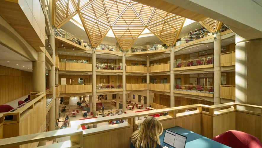 Open, multi‑level library atrium with a wooden geodesic skylight and people studying. (informative)